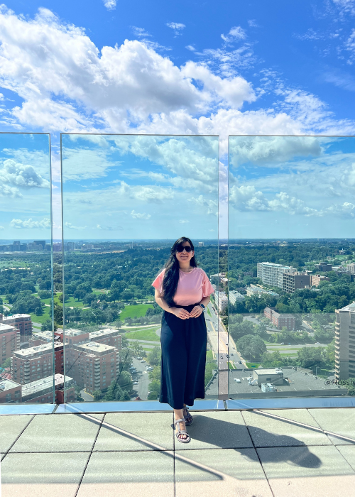 Photo of an international student on a terrace showing the northern Virginia landscape behind her
