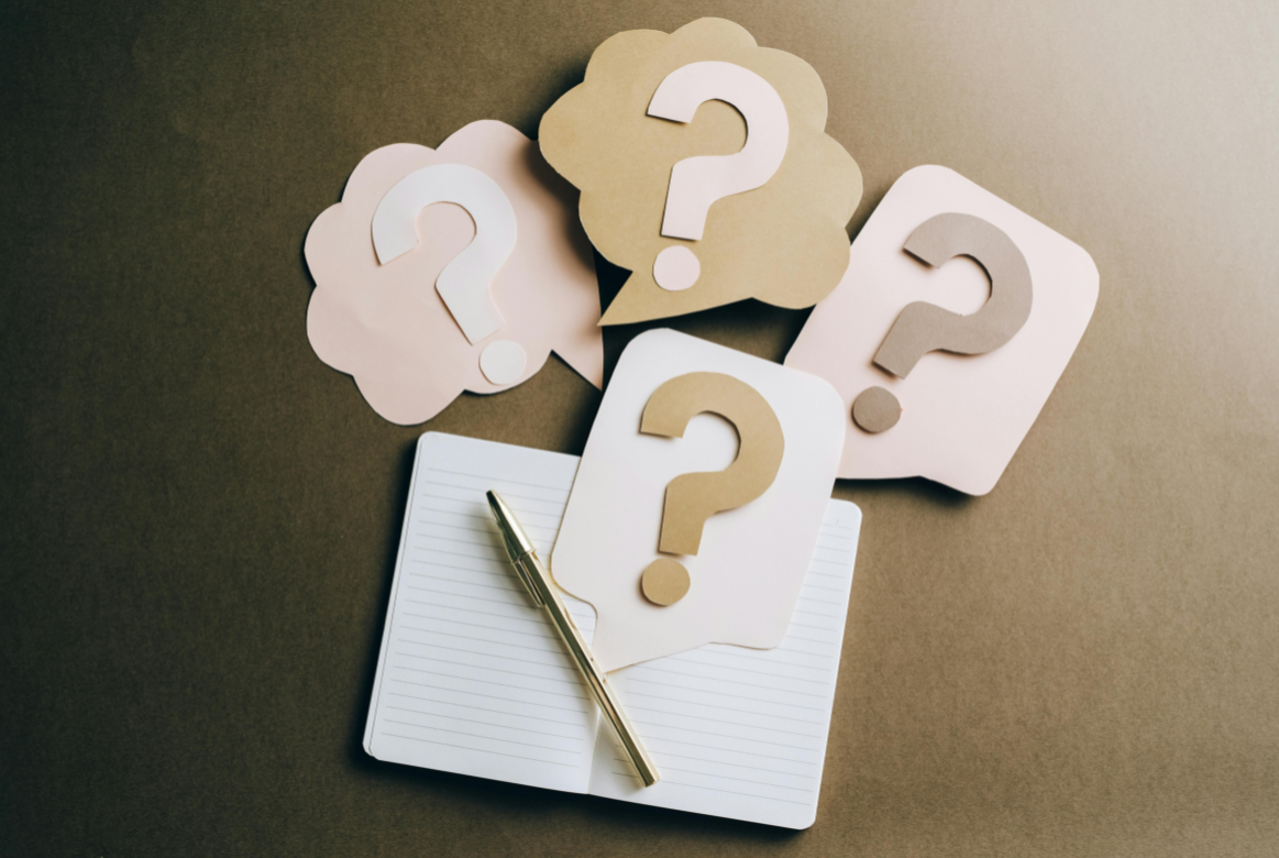 Question marks Paper cut outs of question marks next to a notebook