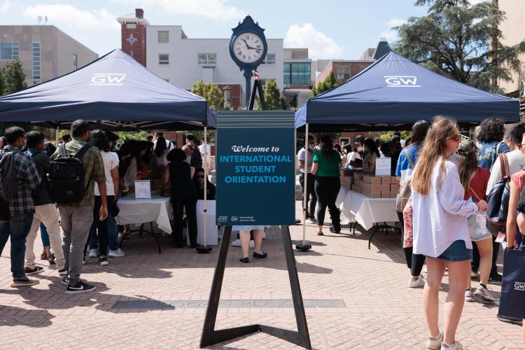 A sign reading "Welcome to New International Student Orientation" in an outdoor plaza