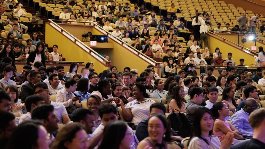 Students sitting in a theatre and shaking hands with the person next to them
