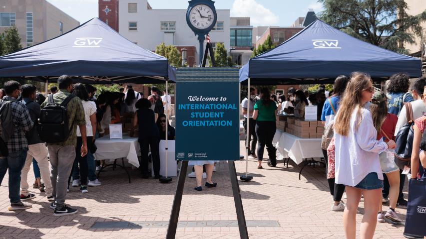 A sign reading "Welcome to New International Student Orientation" in an outdoor plaza